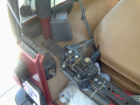 1998 Jeep TJ - A hi-lift jack is stored inside the vehicle, with a license plate visible near the door.