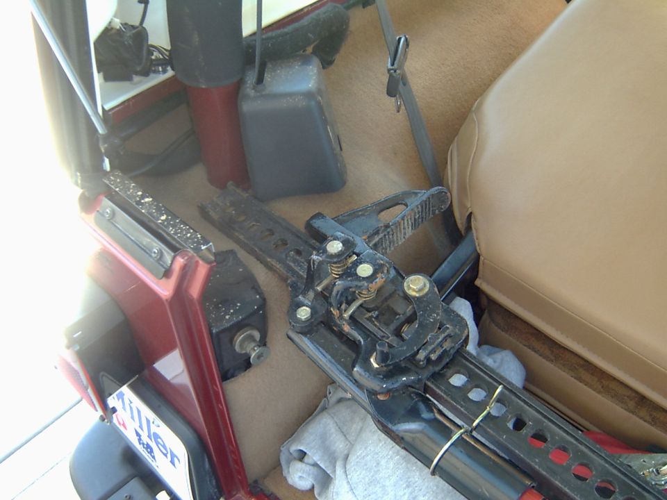 Black seat track and slider mechanism removed onto the tan carpet of a Jeep interior