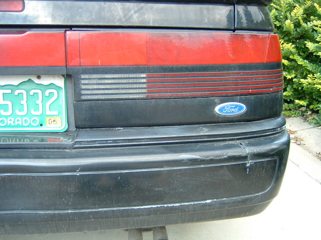 Rear corner of black Ford coupe, Colorado plate ...5332, oval Ford badge on bumper