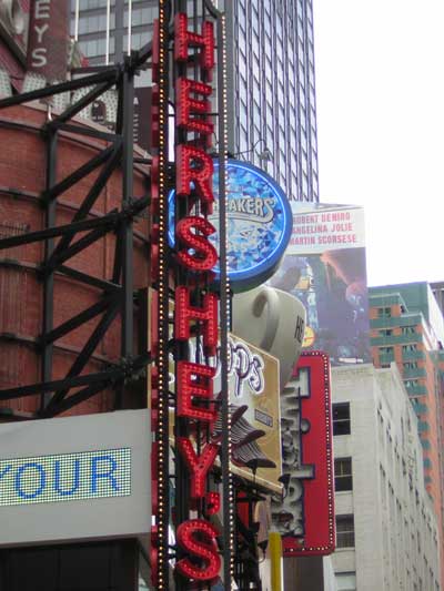 1995 Ford Bronco - Vertical Hershey's sign with red neon letters stands tall in Times Square, New York City.