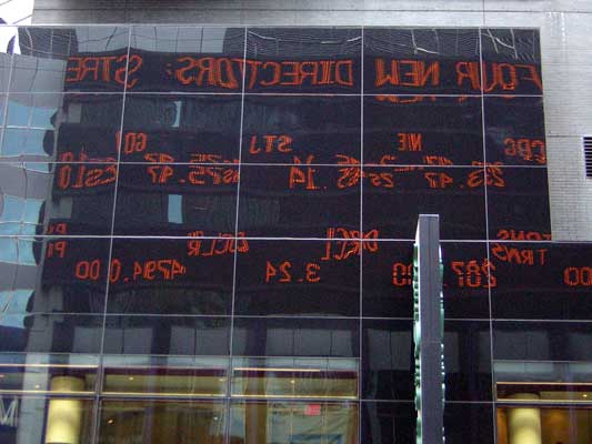 Building facade with a digital stock ticker display showing orange text and numbers