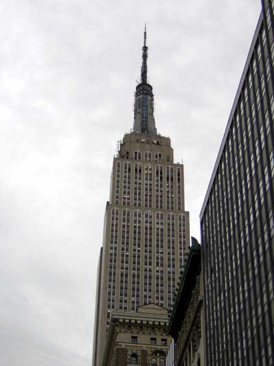1995 Ford Bronco - The iconic Empire State Building stands tall against a cloudy sky, flanked by a modern skyscraper.