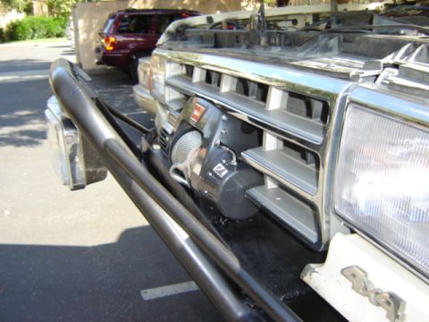 1991 Ford Bronco - A winch is mounted to the front grille guard of a 1991 Ford Bronco, with another vehicle visible in the background.