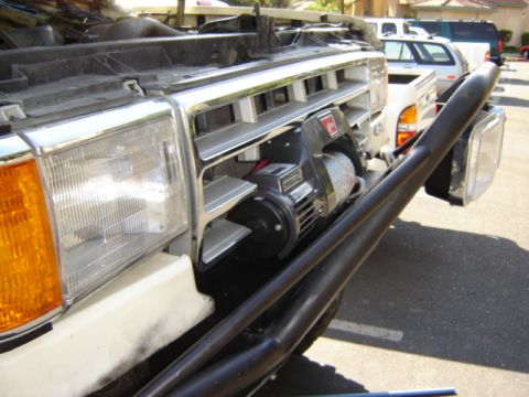 1991 Ford Bronco - This white SUV features a winch mounted behind the grille, with a black bull bar in front.