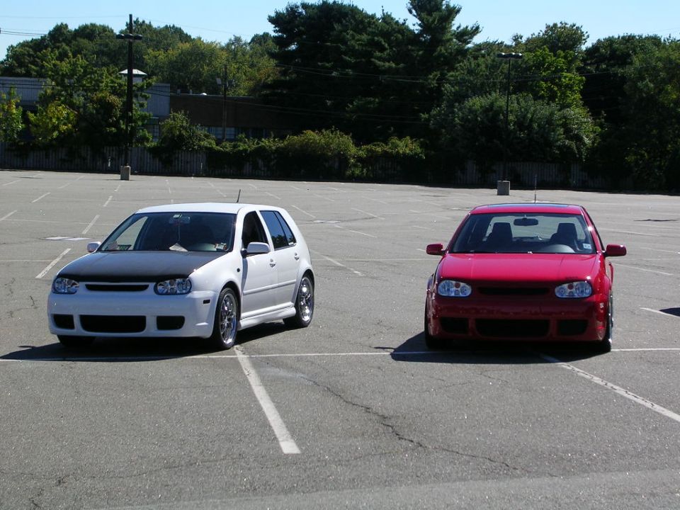White VW Mk4 Golf with carbon hood parked beside a lowered red Mk4 Golf
