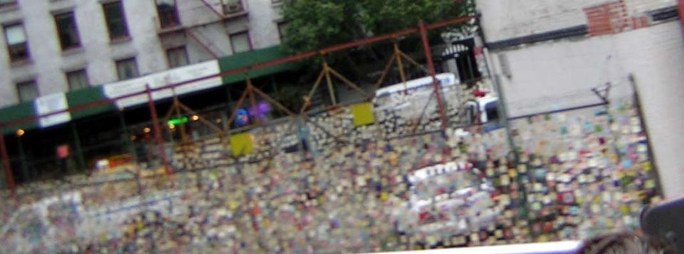 construction scaffolding over a street covered in flyers and posters, with a white van visible behind it