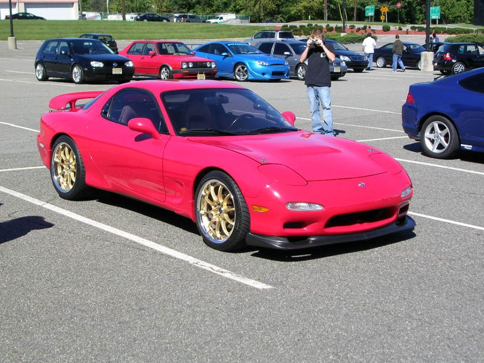 Pink Mazda RX-7 with gold wheels, front 3/4 view
