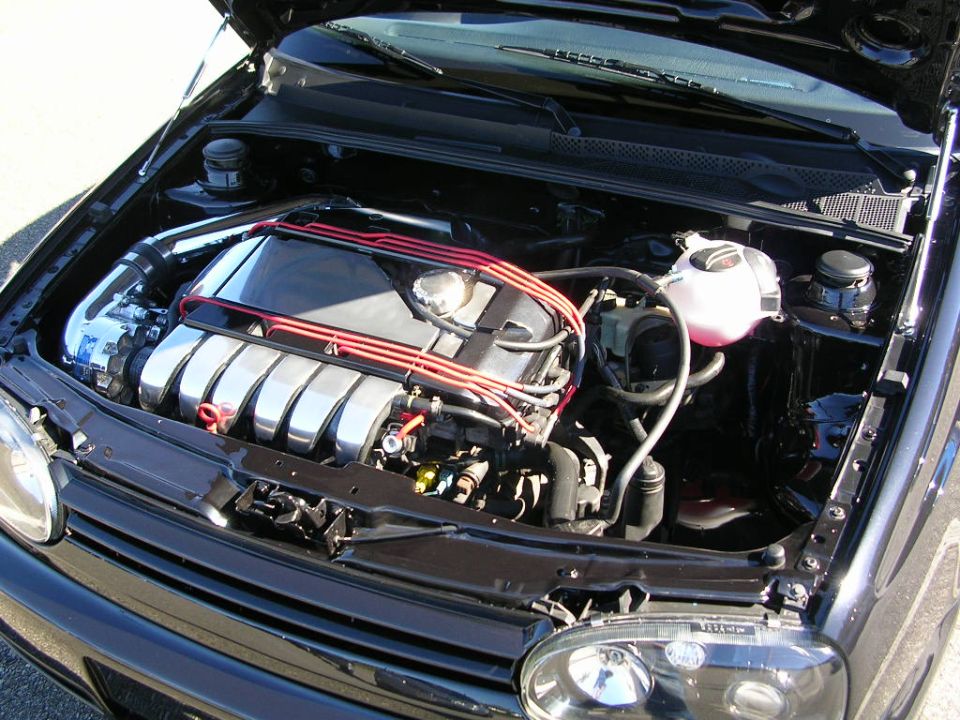 VR6 engine bay in black VW Mk3: polished intake runners, red plug wires, strut bar, white coolant tank