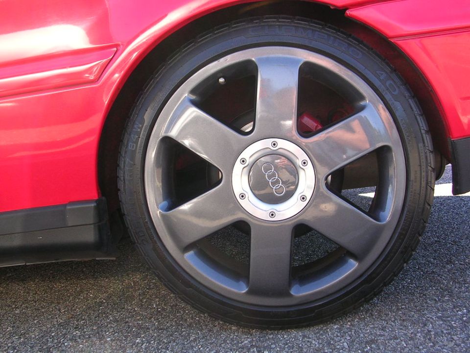 Red car fender and grey Audi wheel with red brake caliper visible