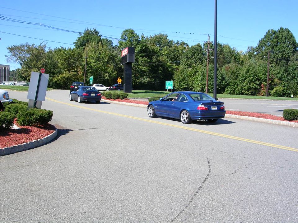 Blue coupe driving on a road with another car behind it