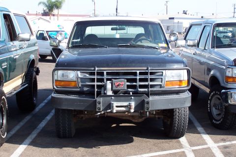 1990 Ford Bronco - Black Ford Bronco with aftermarket winch and brush guard, parked in a lot.