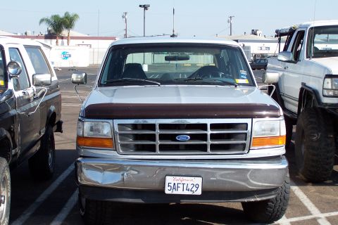 1990 Ford Bronco - This Ford F-Series truck, likely from the early 1990s, is parked between other vehicles.