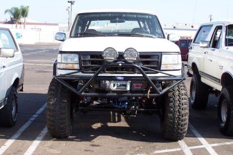 1990 Ford Bronco - Front view of a modified white Ford Bronco from the early 1990s, parked alongside another similar vehicle.
