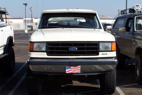 1990 Ford Bronco - Front view of a white 1990 Ford Bronco, parked next to another vehicle.