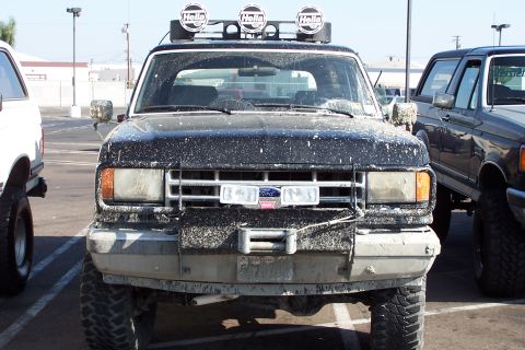 1990 Ford Bronco - Front view of a muddy 1990 Ford Bronco with auxiliary lights and a winch.