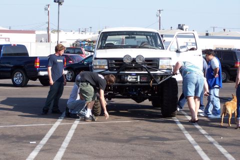 1990 Ford Bronco - Several people examine a heavily modified Ford F-Series truck with oversized tires and a winch.