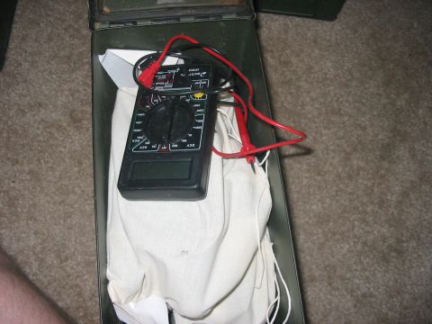 1988 Ford Bronco - A digital multimeter is stored inside a green ammo can with its red leads connected.