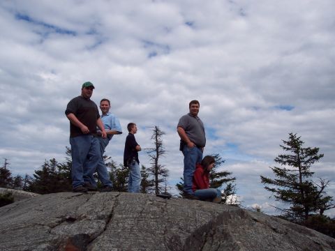 2001 Ford Crown Victoria - A group of friends enjoy a scenic view from a rocky summit under a cloudy sky.