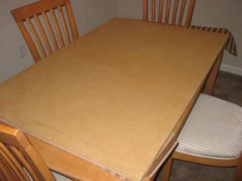 1988 Ford Bronco - A dining table is covered with cardboard, with chairs visible around it.