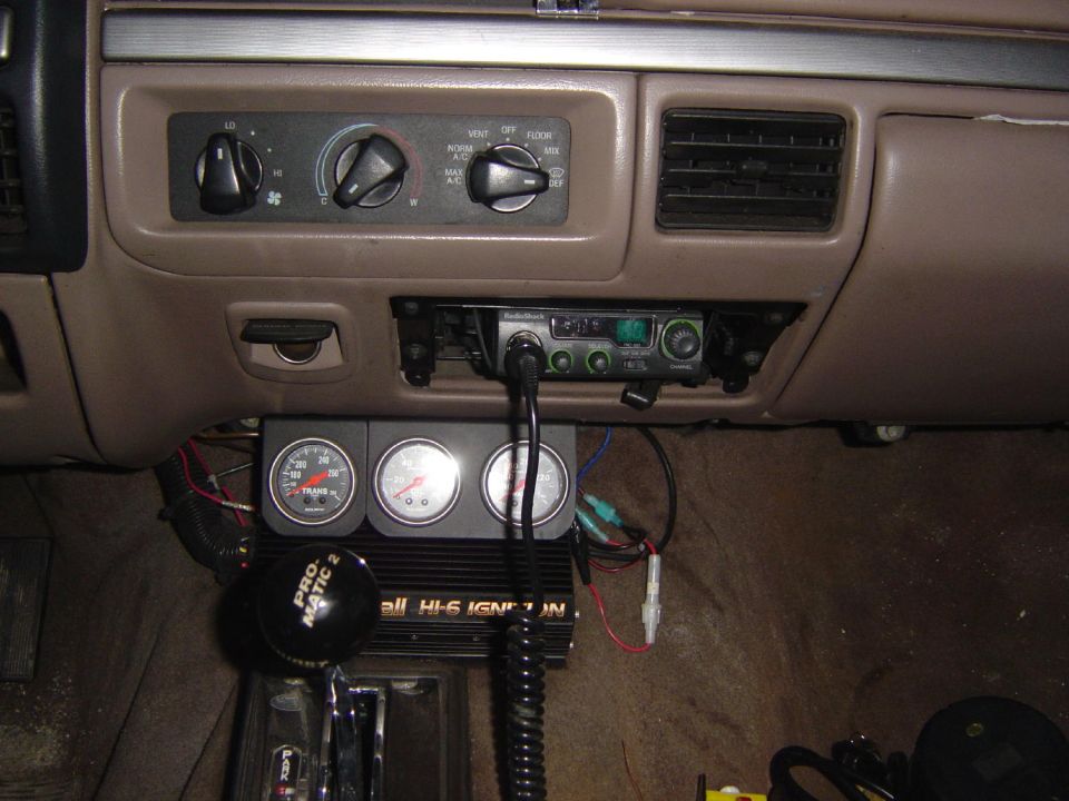 Interior dashboard with CB radio and three gauges, including a tachometer