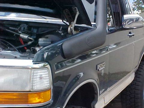 1992 Ford Bronco - A 1992 Ford Bronco is shown from the front 3/4 angle with its hood open, revealing the engine compartment and a snorkel accessory.