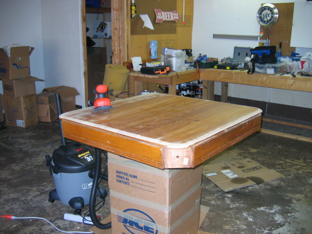 Tabletop on boxes with sander and shop vac nearby in a garage