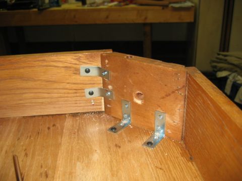1985 Ford LTD Crown Victoria - Metal brackets reinforce a wooden furniture joint, with sawdust scattered on the surface.