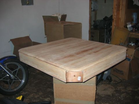 1985 Ford LTD Crown Victoria - A wooden table and a motorcycle wheel are in a cluttered garage setting.