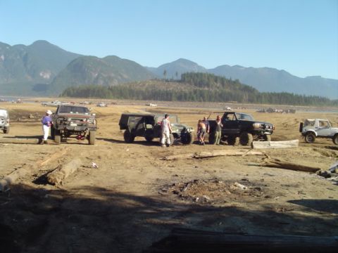 1993 Ford Bronco - A group of off-road vehicles are gathered in a barren landscape under a clear blue sky.