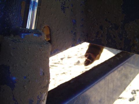 1993 Ford Bronco - Close-up of a dirty blue suspension component, showing a metal cylinder and a hole.