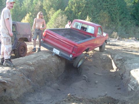 1993 Ford Bronco - A red pickup truck is stuck in a dirt trench while a jeep waits nearby.