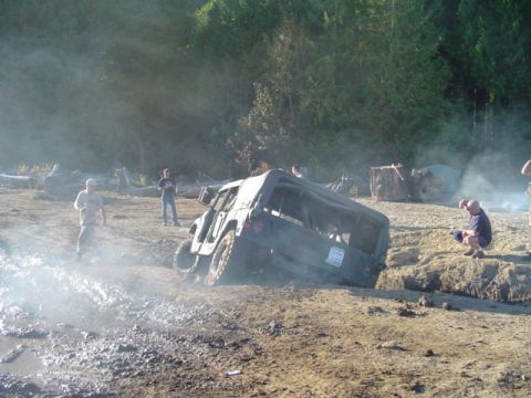1993 Ford Bronco - An off-road vehicle is stuck in a muddy area with several people observing the situation.