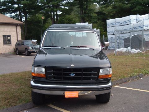 1993 Ford Bronco - A dark-colored Ford truck is parked in a lot with another SUV visible in the background.