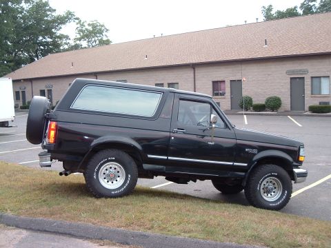 1993 Ford Bronco - Side view of a black 1993 Ford Bronco parked next to a building.