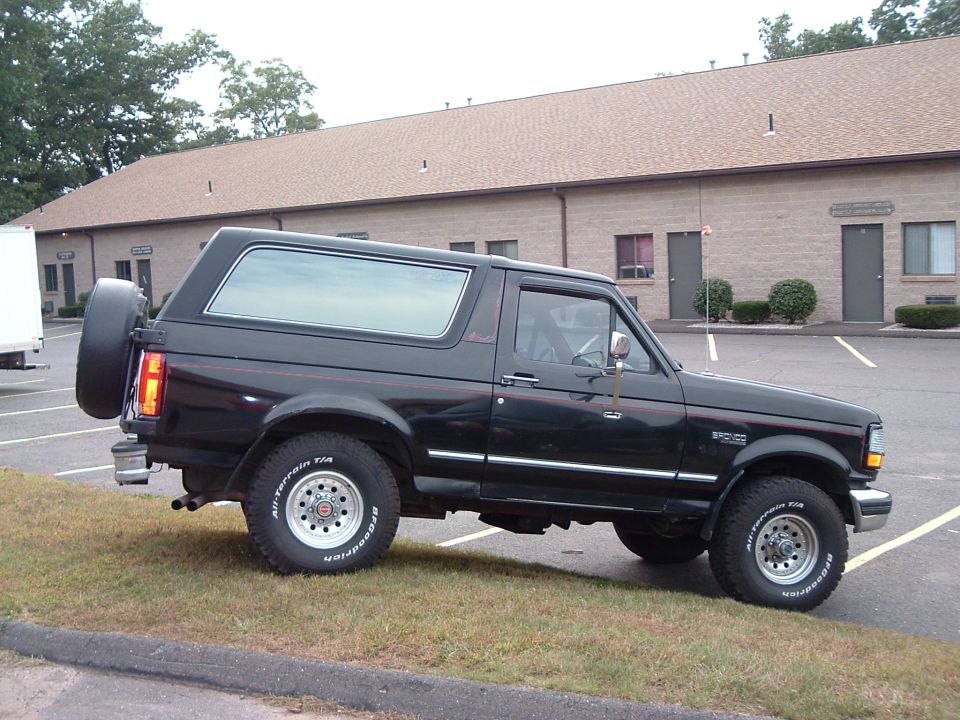 Black 1993 Ford Bronco parked on grass with a building in the background