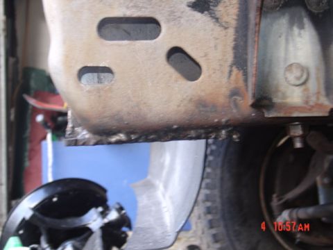 1991 Ford F-150 - Detail of a heavily rusted vehicle frame, showing structural components and a tire.