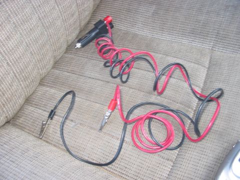1988 Ford Bronco - Car interior with tan fabric seats and a coiled red and black wire set with alligator clips and a cigarette lighter plug.