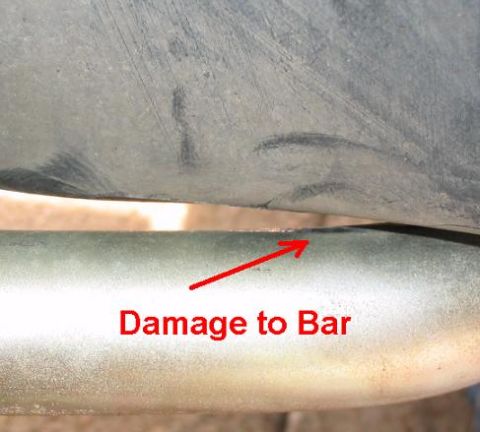 1999 Ford Crown Victoria - A red arrow points to damage on a metal bar, with text indicating 'Damage to Bar' and a SuperMotors logo at the bottom.