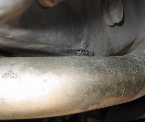Close-up of exhaust pipe with undercarriage detail. SUPERMOTORS.NET logo visible