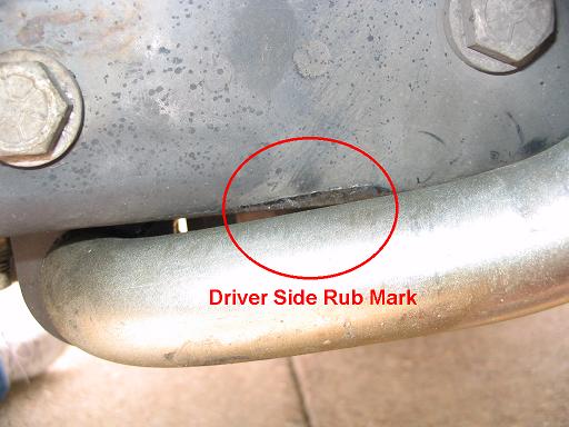 Close-up of a metal part with a red circle highlighting a driver side rub mark and text