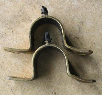 1999 Ford Crown Victoria - Two metal brackets with bolts are shown against a concrete background. Supermotors.net logo is present.