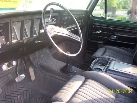 1978 Ford Bronco - The interior of a green 1978 Ford Bronco features a dashboard with rectangular vents, a large steering wheel, and a floor-mounted shifter.