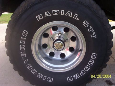 1978 Ford Bronco - A close-up view of a Cooper Discoverer Radial STT tire mounted on a chrome wheel, with a date stamp visible.