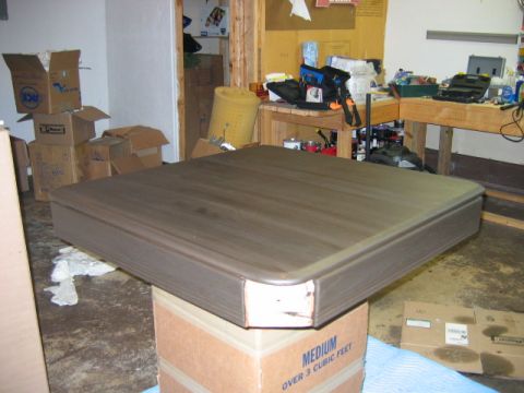 1985 Ford LTD Crown Victoria - A wooden tabletop rests on two stacked cardboard boxes in a workshop setting with various items in the background.