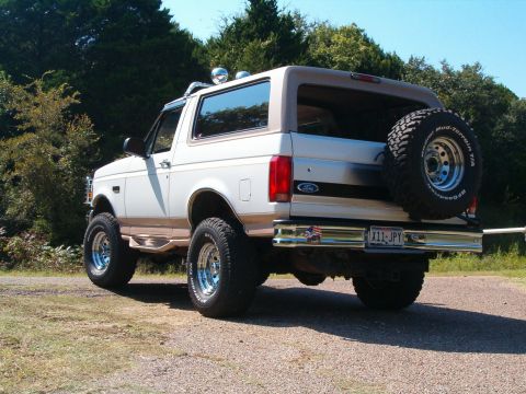 1996 Ford Bronco - The rear view of a white 1996 Ford Bronco with tan trim and a spare tire mounted on the back.