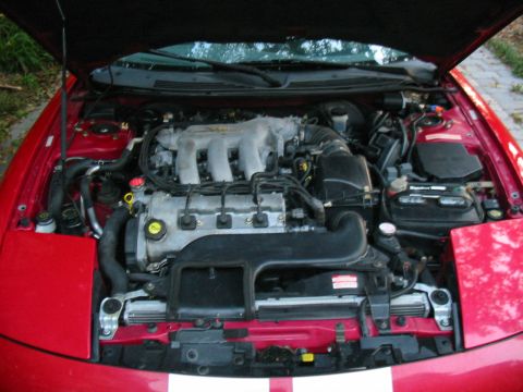 1997 Ford Probe - The engine bay of a red 1997 Ford Probe is shown with the hood open.