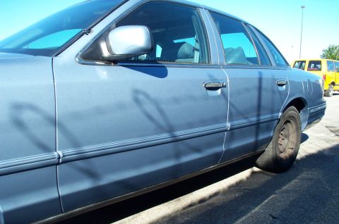 1991 Ford LTD Crown Victoria - Side profile of a blue 1991 Ford Crown Victoria LTD showing its body lines and a flat tire.