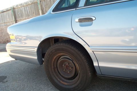1991 Ford LTD Crown Victoria - The rear side of a light blue sedan shows its body style and chrome trim, but the year is not definitively 1991.