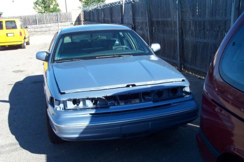 1991 Ford LTD Crown Victoria - A blue sedan, likely from the early 90s, is parked outdoors with its front end partially disassembled.