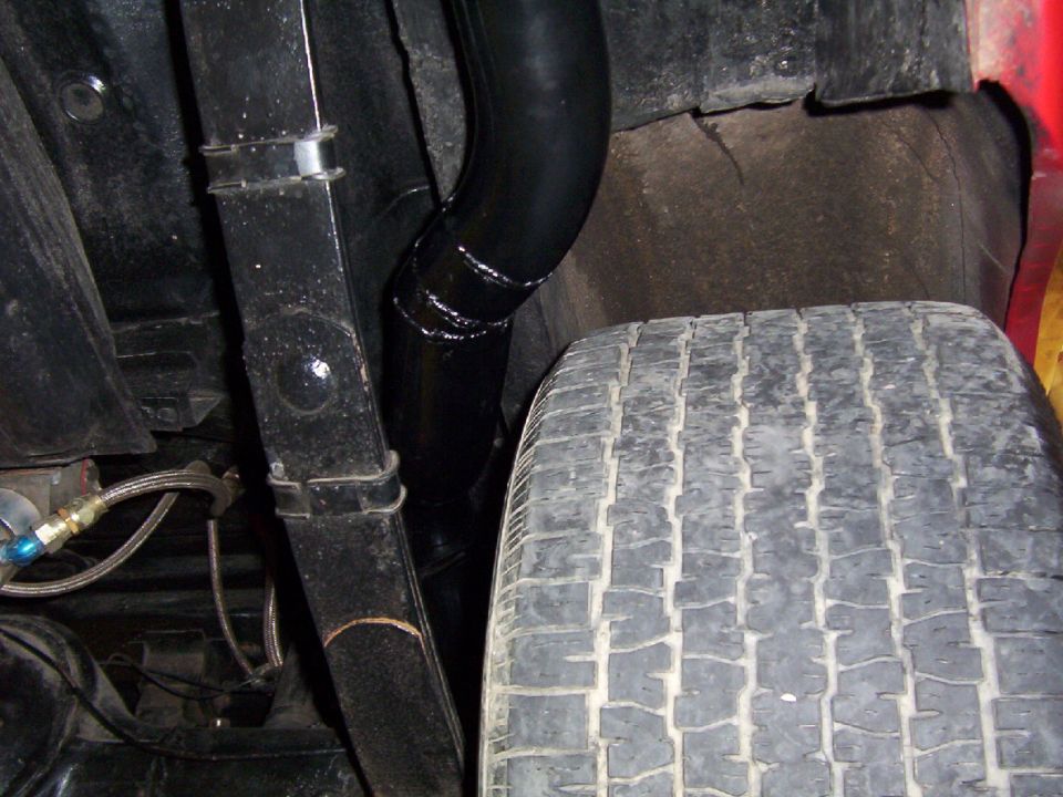 Undercarriage view showing a tire, black exhaust pipe, and suspension components